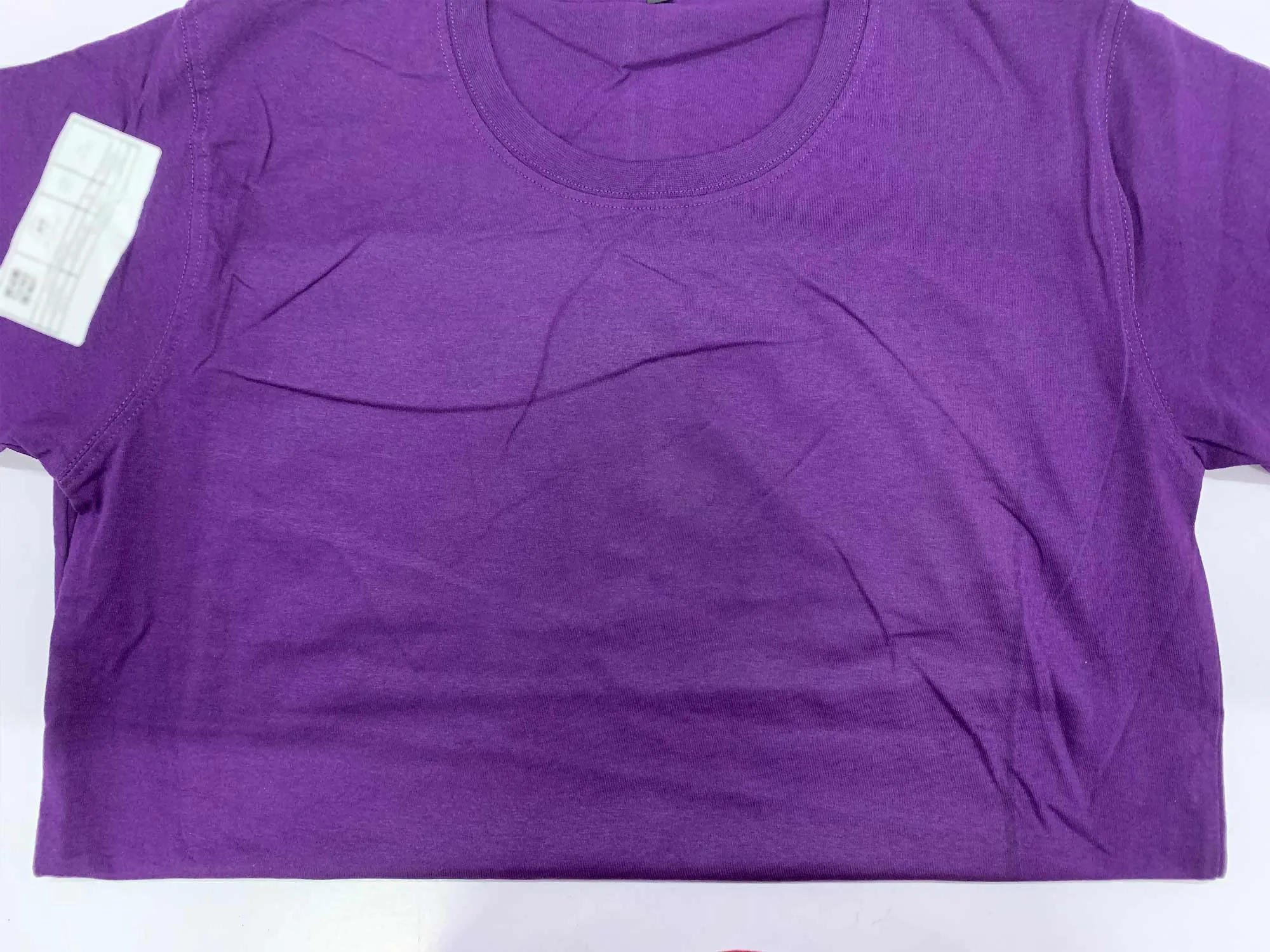 Purple t-shirt showing visible fusing/coating marks from DTG pre-treatment process around the print area